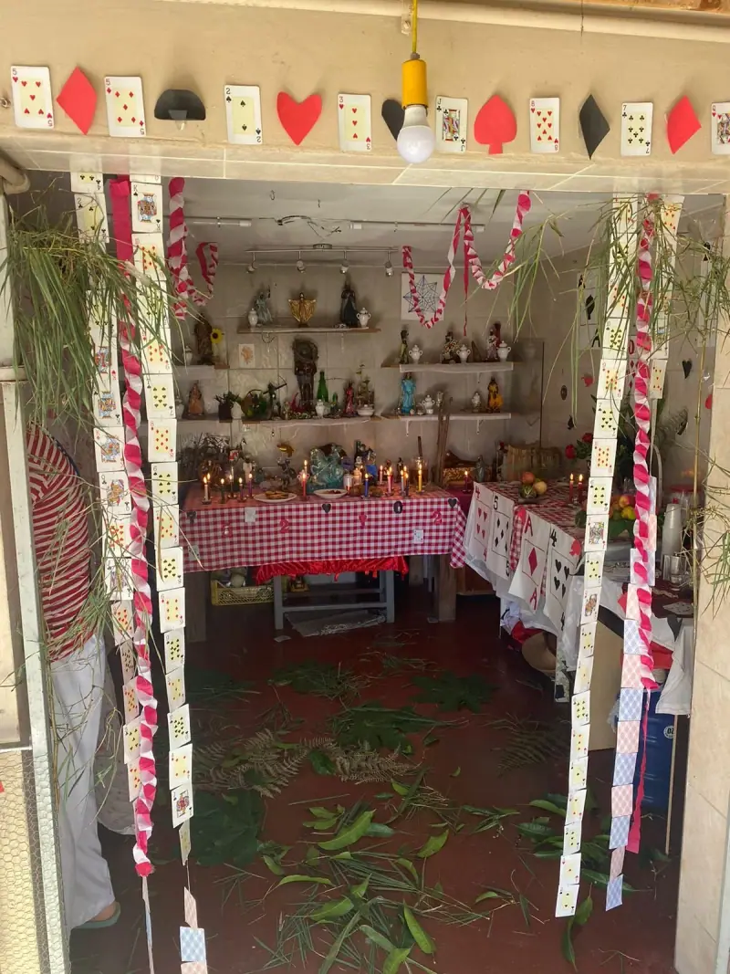 Entrada do terreiro enfeitada com cartas de baralho e fitas, com o congá ao fundo